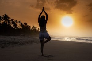 person meditating in sunset