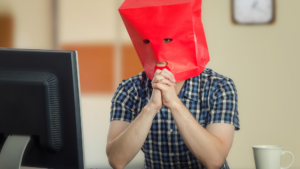 man with red paper bag over head
