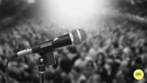 black and white photo of microphone and blurred audience