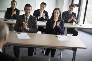 Business colleagues clapping hands in learning seminar office classroom