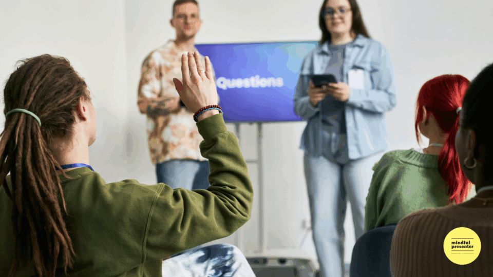two presenters and man raising hand to ask a question