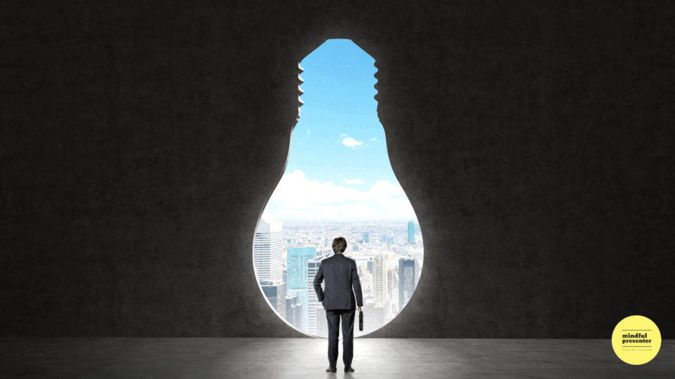 Man standing in front of an opening in the shape of a giant light bulb looking at the city