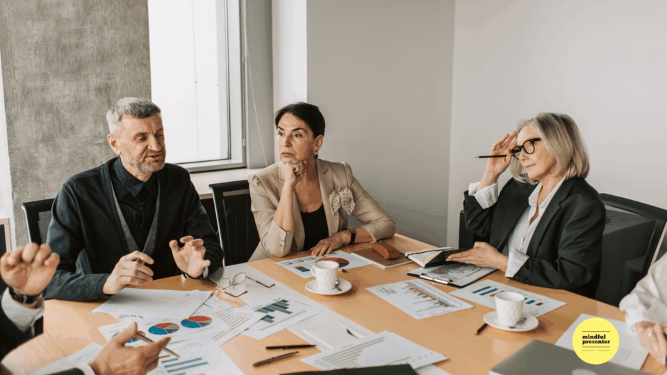 People sitting around a table with papers and cups on it.