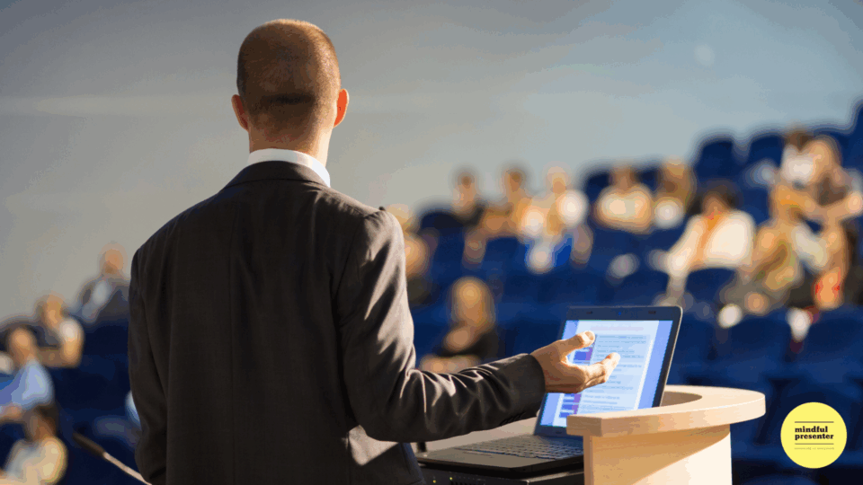 Public speaker back view at podium with laptop