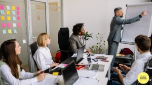 Man writing on flip chart in meeting