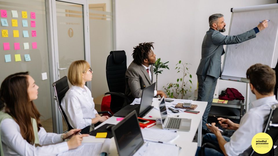 Man writing on flip chart in meeting