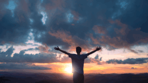 man standing facing sunset with arms wide open