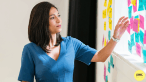 woman putting post it note on whiteboard