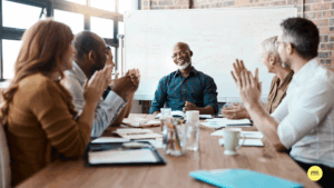 people sitting around table in meeting room clapping