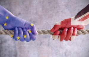 Tug of war between hands painted with UK and European flags