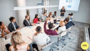 woman standing at front of meeting table presenting