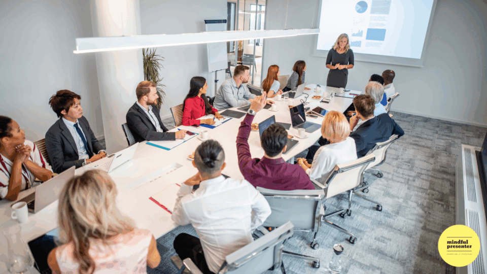 woman standing at front of meeting table presenting