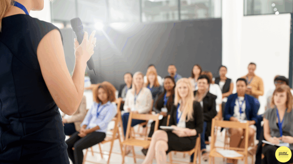 woman presenting with microphone to large audience