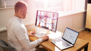 man presenting on line with two laptops