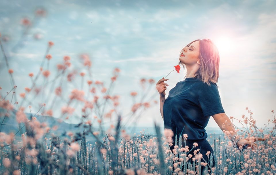 woman smelling flower in a field