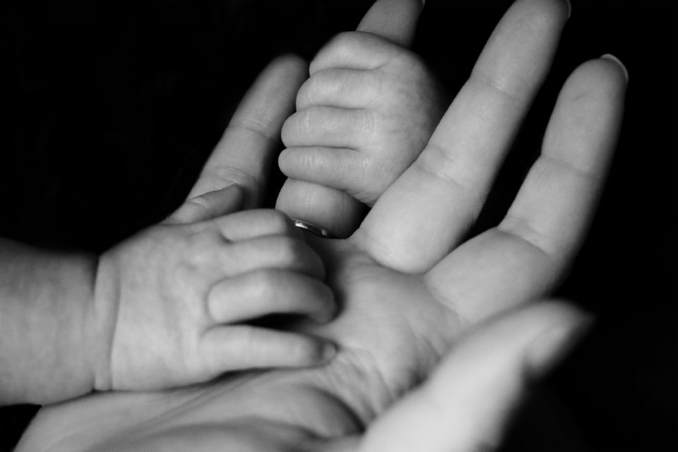 black and white photo of mother and baby hand