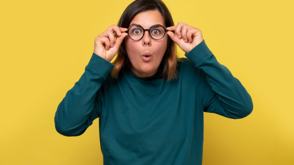 woman looking surprised holding spectacles