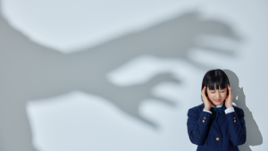 woman covering ears with scary shadow of hands appearing