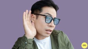 man wearing glasses holding is hand to his ear to listen