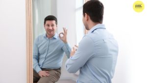 Man looking in mirror making ok sign