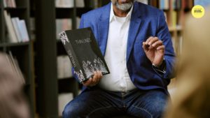 man sitting down holding a book called Thin Line
