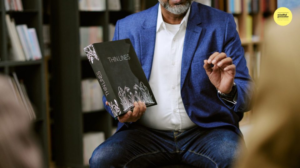 man sitting down holding a book called Thin Line