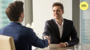 two men seated shaking hands